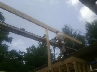 Carpenter setting a ridge beam over a new addition frame — Ice Dam Removal by Roofing Brothers in Glade Hill