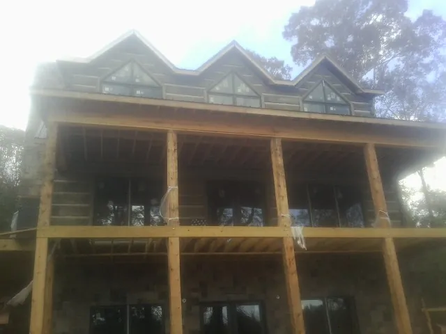 Dormers and porch framing on a large log home under construction — Roof Coating work by our crew in Glade Hill