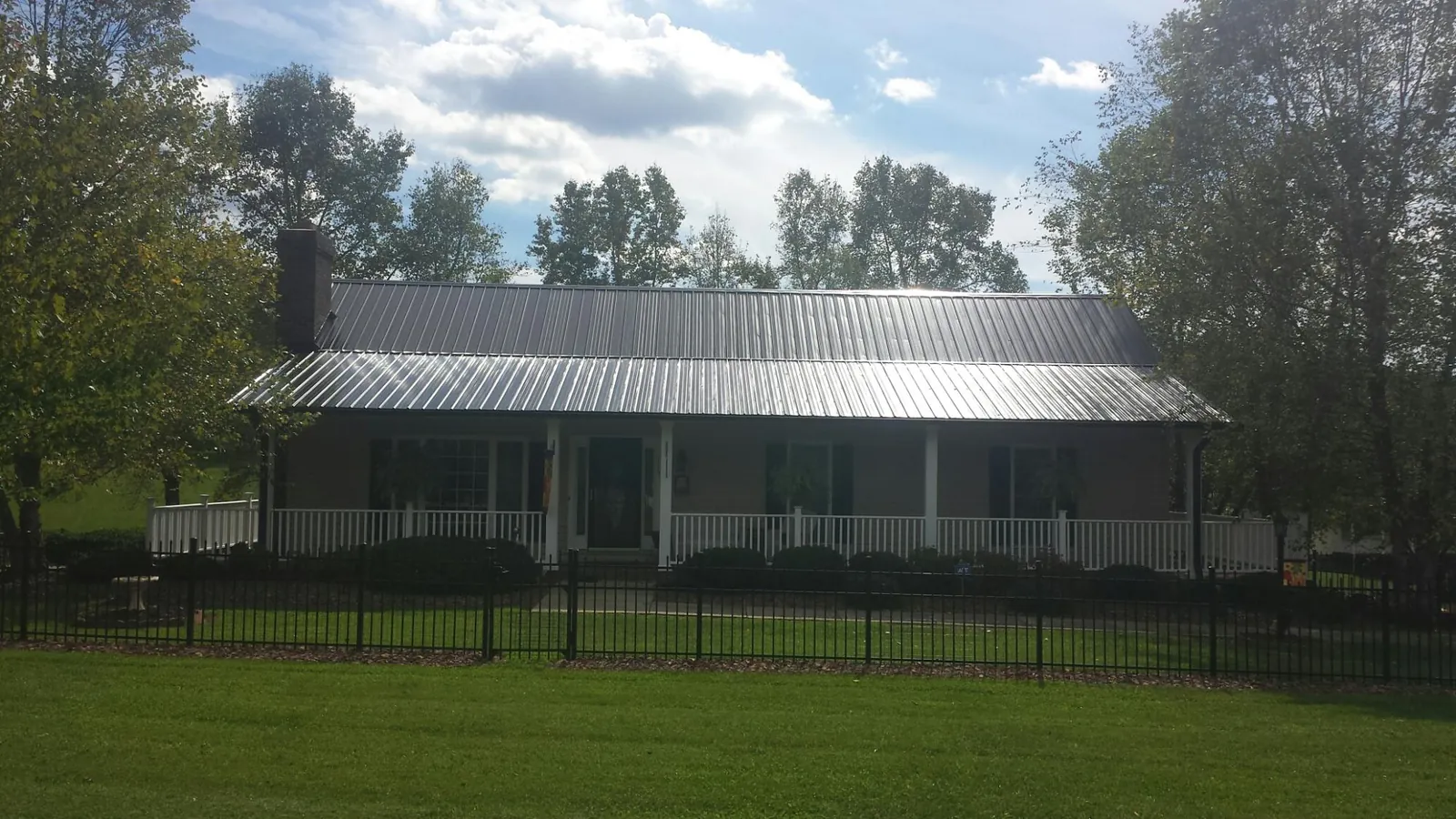 Gray metal roof on a brick ranch with a full width front porch — Gutter Guard Installation work by our crew in Glade Hill