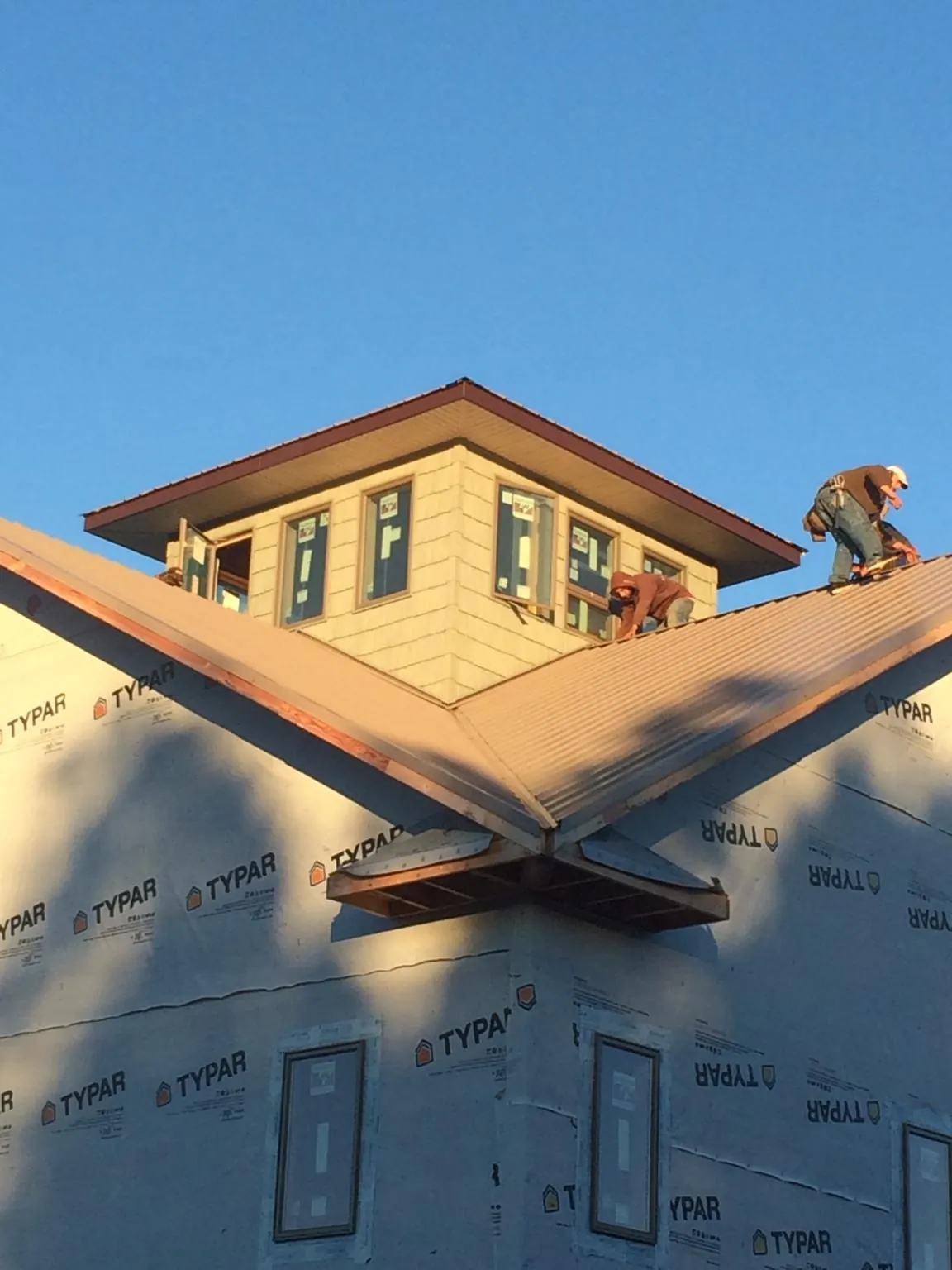 Roofers working around a rooftop cupola on a new metal roof at sunset — Roof Waterproofing in Glade Hill by Roofing Brothers